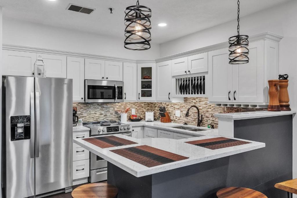 a kitchen with white cabinets and a stainless steel refrigerator at Grand Wood Suites - 2nd Floor Front Side Signature Suite 201 in Nashville