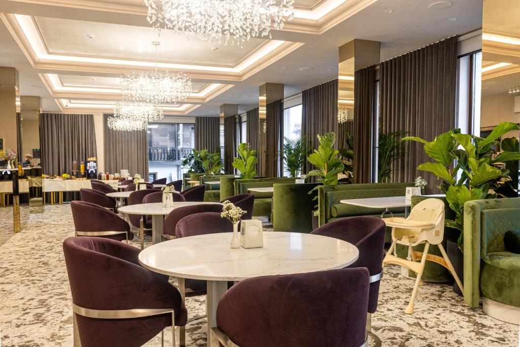 a restaurant with tables and chairs and a chandelier at MARION SPA Hotel & Spa - RENOVATION - Rooms, SPA area, Swimming pool, Reception, Restaurant, Lounge Bar, Hookah bar, Children's room, Parking, SPA and Breakfast included in the price in Bukovel