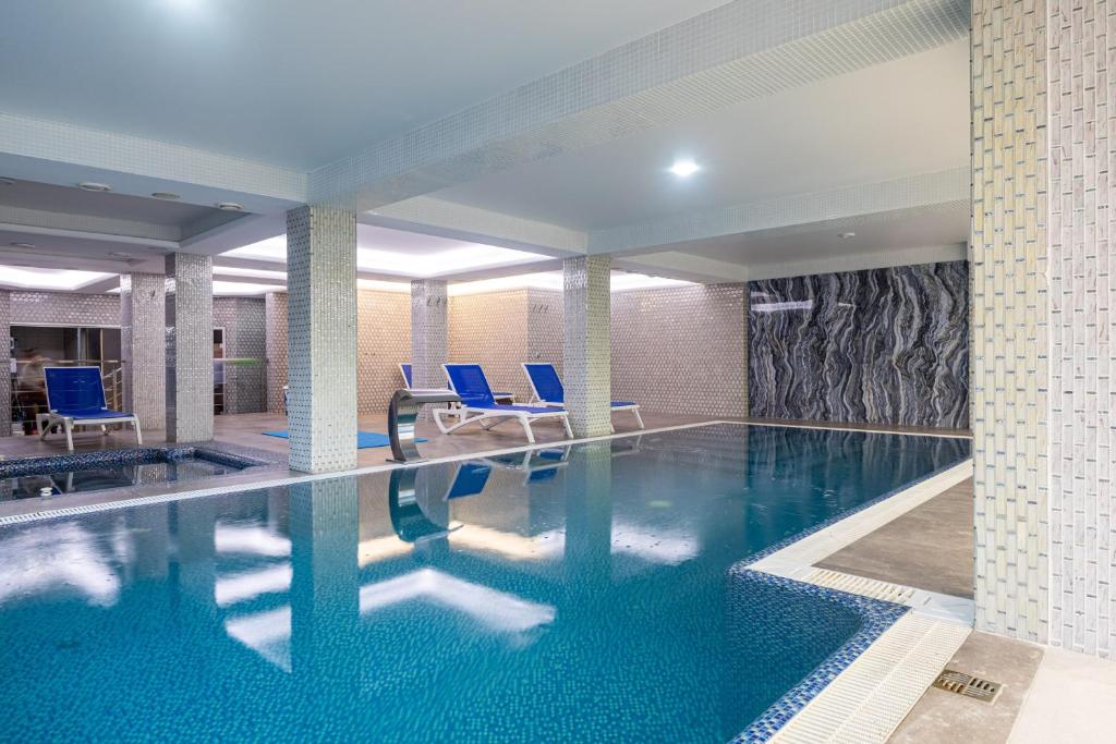 a large swimming pool with blue chairs in a building at MARION SPA Hotel & Spa - RENOVATION - Rooms, SPA area, Swimming pool, Reception, Restaurant, Lounge Bar, Hookah bar, Children's room, Parking, SPA and Breakfast included in the price in Bukovel