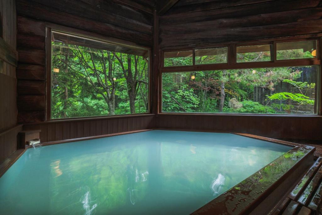 bañera de hidromasaje en una habitación con 2 ventanas en Takamiya Hotel Hammond, en Zao Onsen