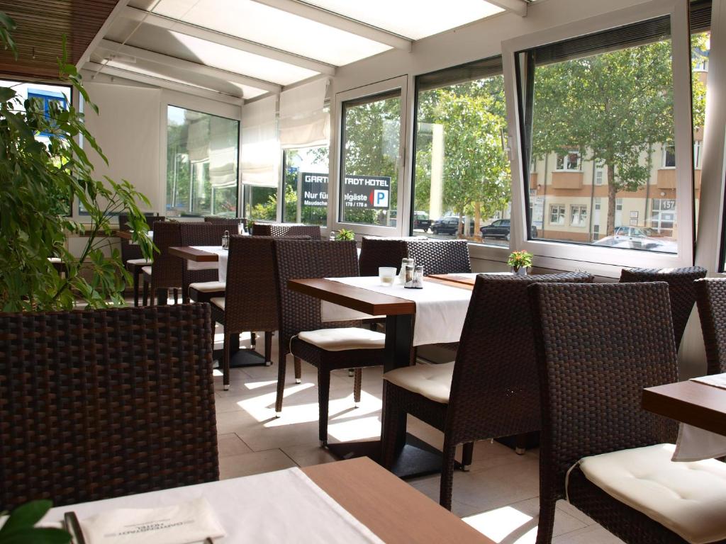 a restaurant with tables and chairs and windows at Gartenstadt Hotel in Ludwigshafen am Rhein