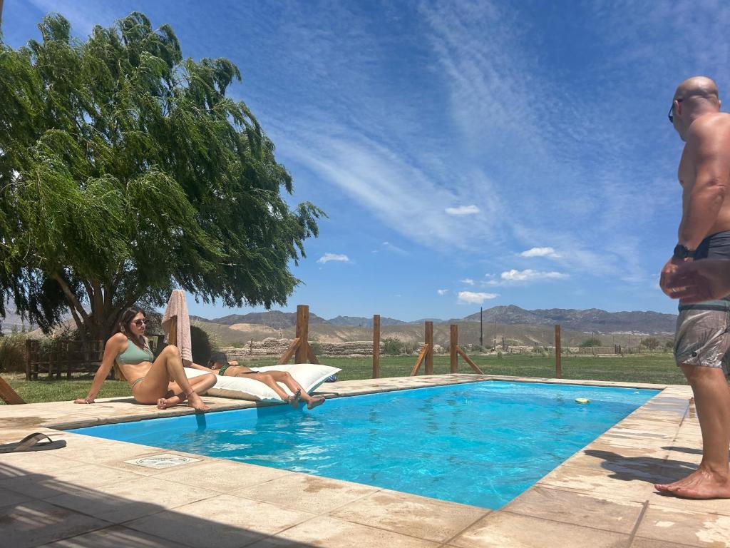 un uomo e una donna seduti accanto a una piscina di El Campito Tiny House de lujo a Rodeo
