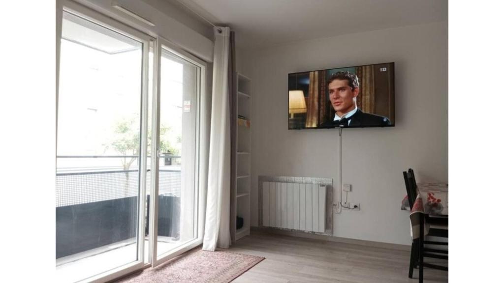 a living room with a tv on a wall with a window at T2 idéal étudiant + pro + parking protégé sous-sol in Thouaré-sur-Loire