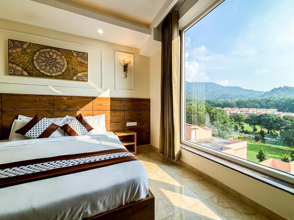 Un dormitorio con una cama y una ventana grande. en Hotel Nirvana Bliss, Behind Parmarth Niketan, en Rishīkesh