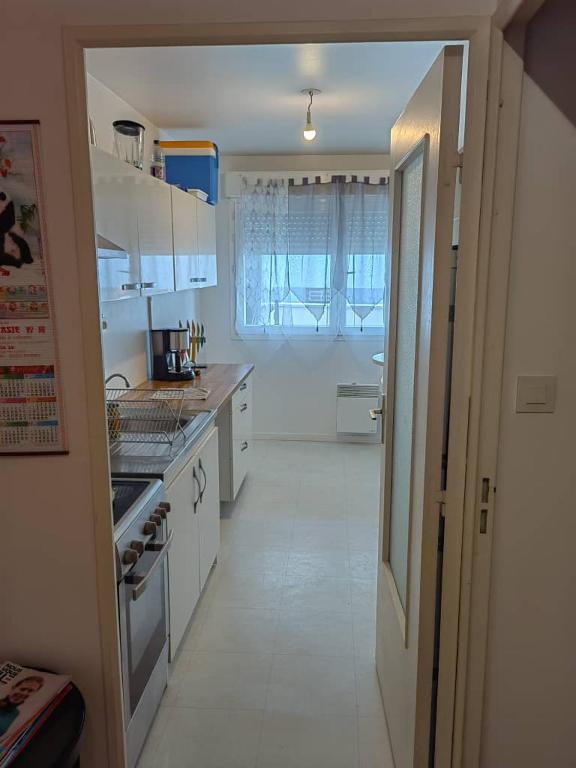 Il comprend une cuisine avec des placards blancs et du carrelage blanc. dans l'établissement Les Lilas, à Chantepie