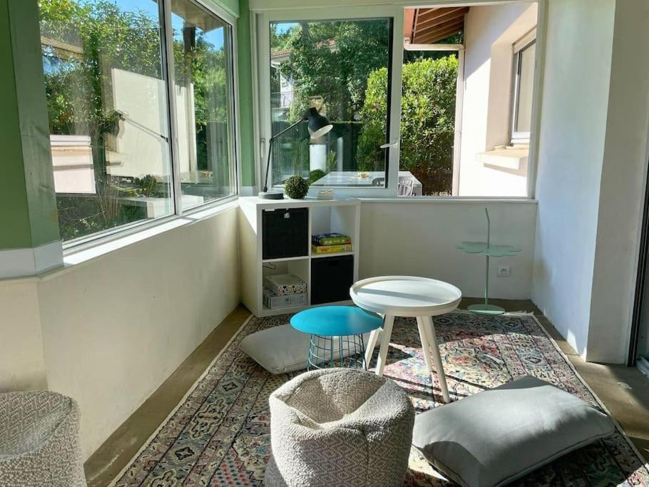 Cette chambre comprend une table, un tabouret et quelques fenêtres. dans l'établissement MAEVA - Belle maison au centre ville à deux pas du lac, à Soorts-Hossegor