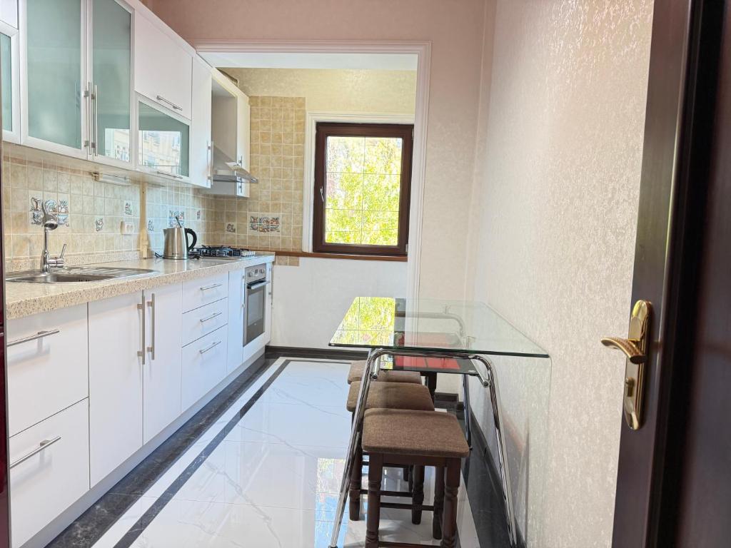 a kitchen with white cabinets and a glass table at CHEKHOV APARTMENT in Tashkent