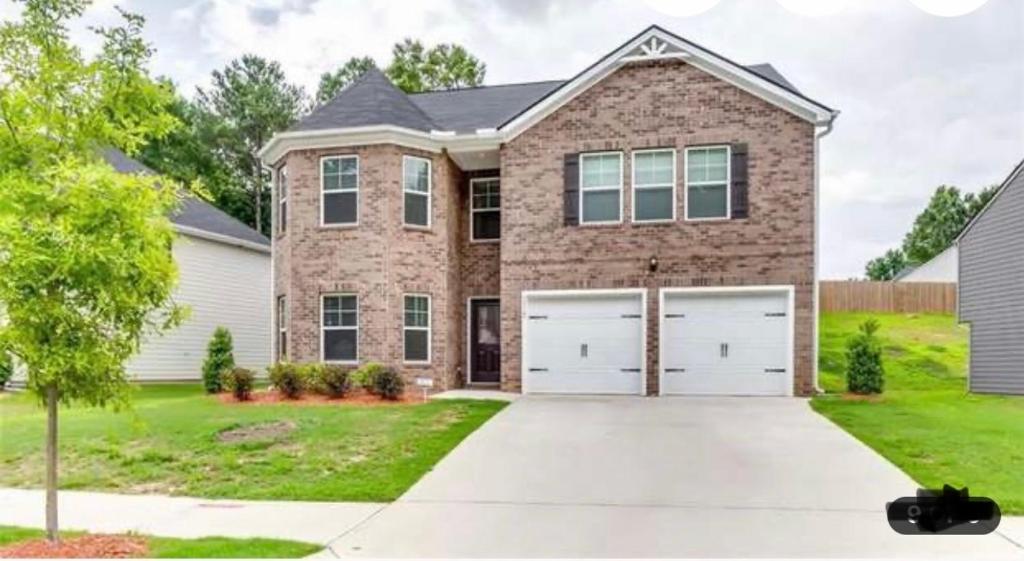 a brick house with two garage doors at Exquisite 5 Bedroom Near Airport in Ellenwood
