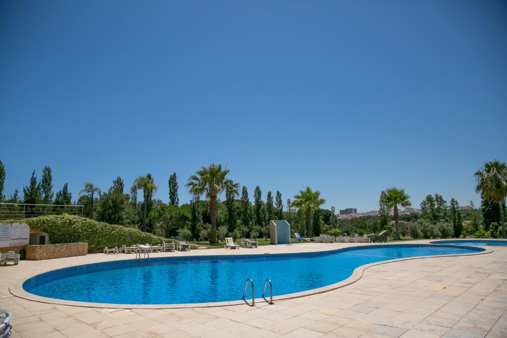 a swimming pool in a resort with palm trees at Sunny Condo-Pool by Algarve Dream Holidays in Albufeira