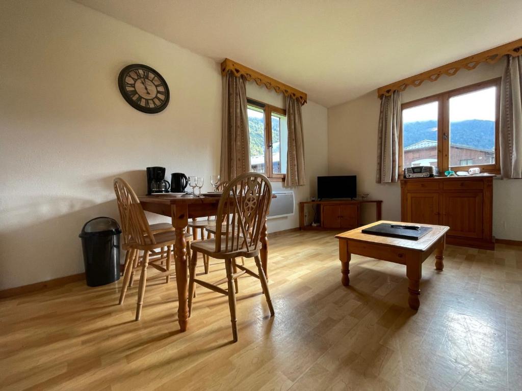 une salle à manger avec une table, des chaises et une horloge dans l'établissement Appartement 1 ch, piscines, parking, animaux acceptés - FR-1-624-107, à Samoëns