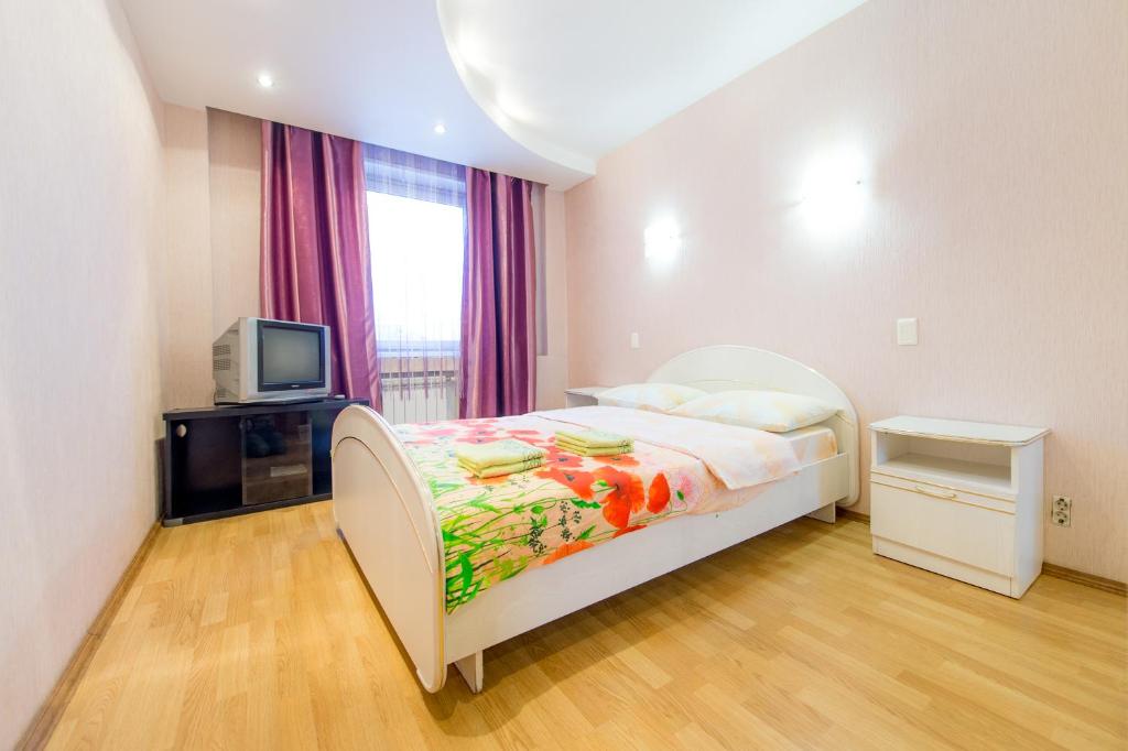 a bedroom with a bed and a tv and a window at Five Stars Monakova in Chelyabinsk