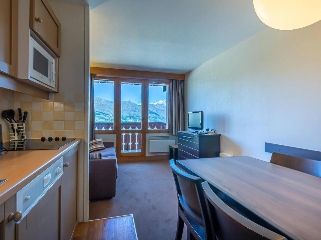 une cuisine avec une table et des chaises dans une pièce dans l'établissement Appartement cosy 25m² 2 pièces pour 4 pers avec balcon - La Plagne-Tarentaise - FR-1-353-132, à La Plagne Tarentaise