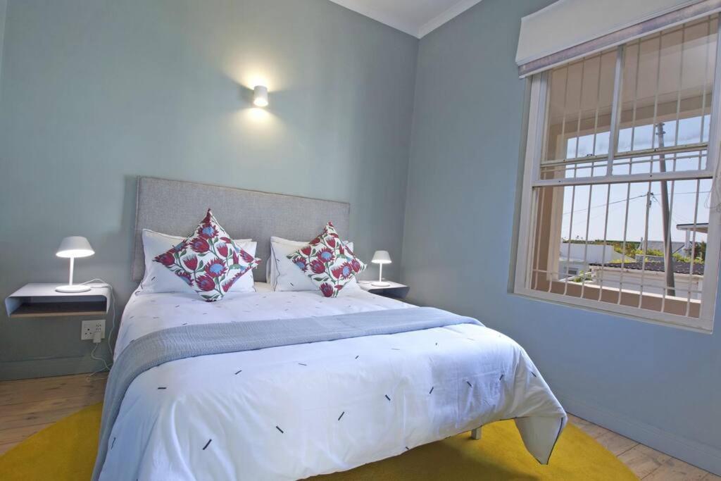 1 dormitorio con 1 cama grande con almohadas y ventana en Two Penguins, en Ciudad del Cabo