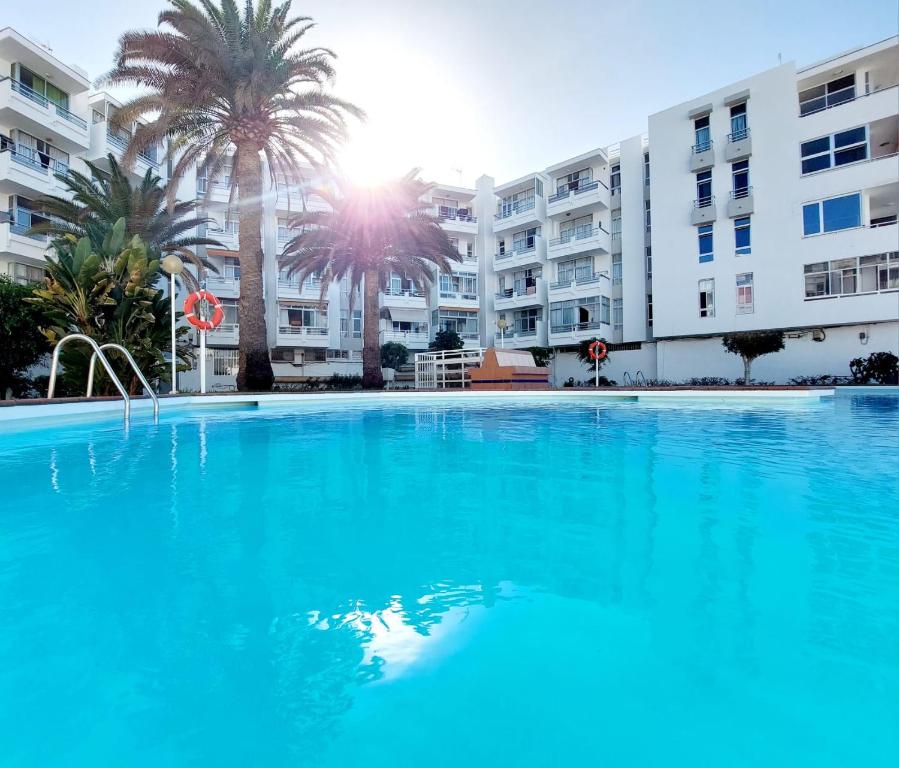 a large swimming pool in front of a building at Apartamento céntrico con playa y piscina in Playa del Ingles