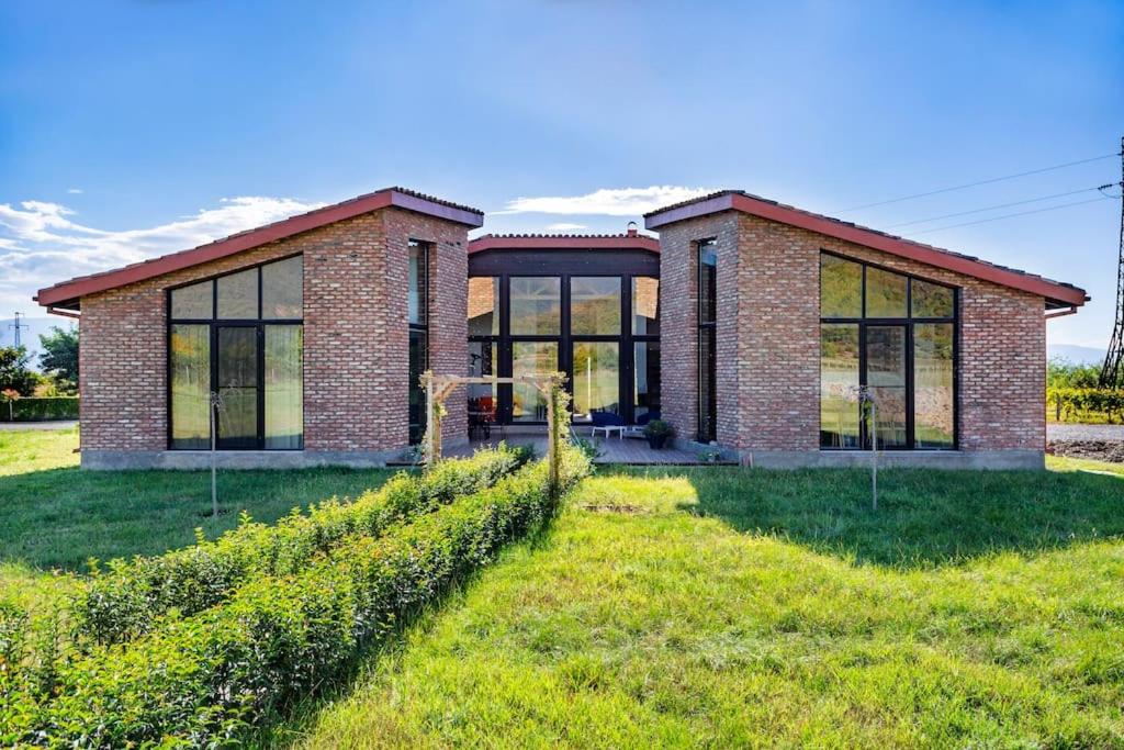 a brick house with windows and a grass field at Villa Chateau Artwine in Art'ana