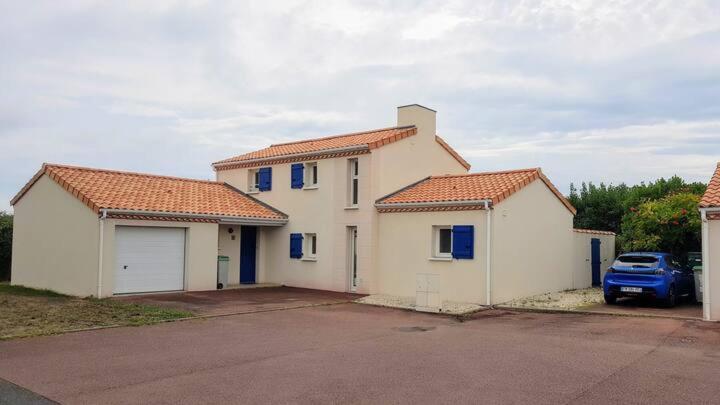 ein weißes Haus mit blauen Fenstern und einem blauen Auto in der Unterkunft Maison spacieuse proche Nantes 7 personnes in Sainte-Luce-sur-Loire