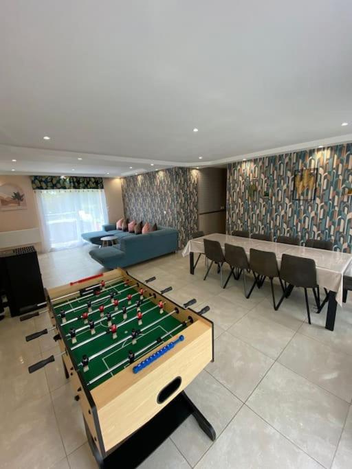 Cette chambre comprend une table de billard et des chaises. dans l'établissement Grande maison tout confort 24 h - jardin et calme, à Voivres-lès-le-Mans