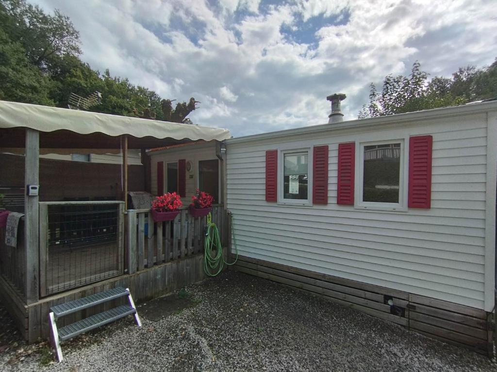 Une caravane blanche avec volets rouges et une maison dans l'établissement Ongi etorri-cures et vacances, à Cambo-les-Bains