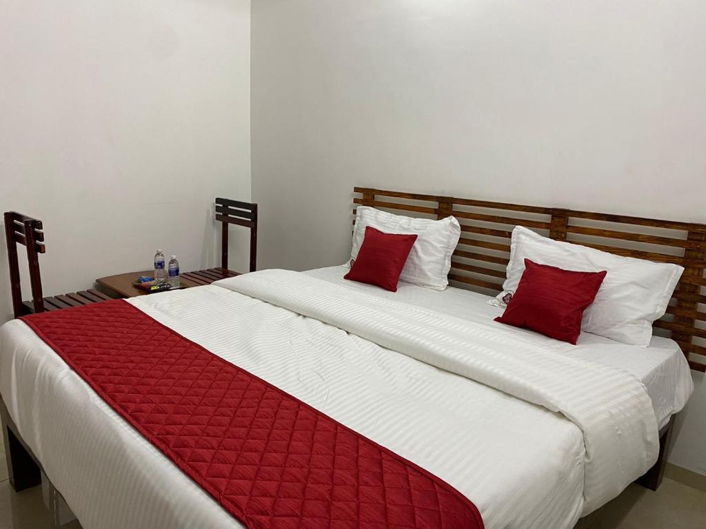 une chambre avec un grand lit blanc avec des oreillers rouges dans l'établissement Luna Park & Resort, à Kottakupam