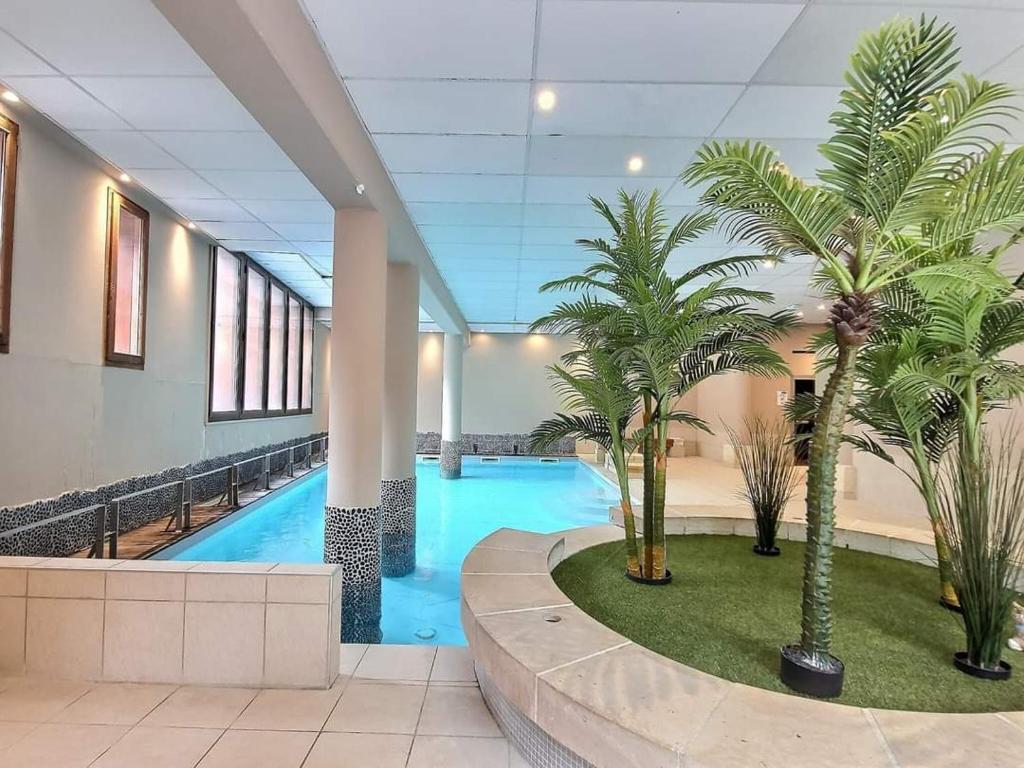un hall d'entrée avec une piscine avec des palmiers dans l'établissement Superbe appartement avec piscine au centre St lary village, à Saint-Lary-Soulan