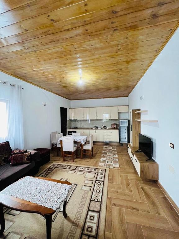 a living room with a wooden ceiling and a kitchen at Bert-House close to the sea in Lezhë