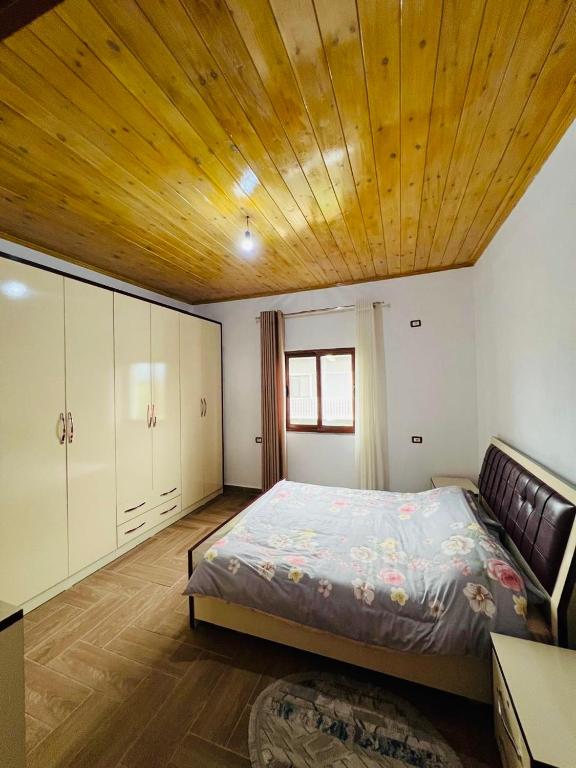a bedroom with a large bed with a wooden ceiling at Bert-House close to the sea in Lezhë