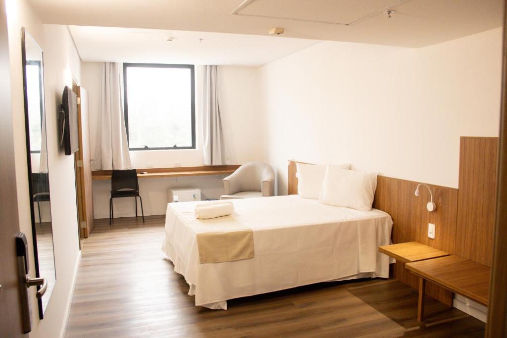 a bedroom with a large white bed and a window at Centro Sul Express Hotel in Lagarto