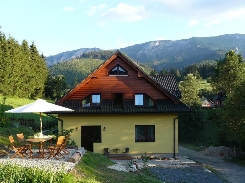a house with a table and chairs and an umbrella at Privát Za Lesíkom in Ždiar