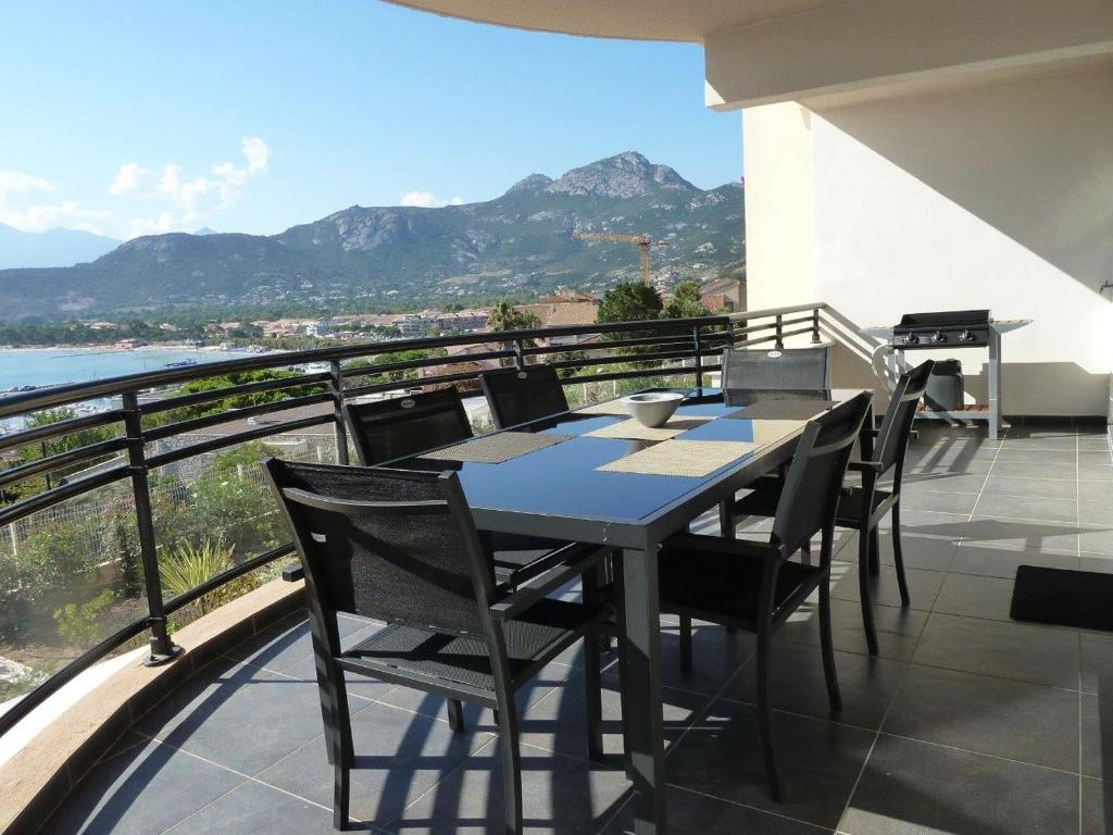 ein Tisch und Stühle auf einem Balkon mit Aussicht in der Unterkunft Appartement vue mer - 2ch 2sdb - Parking - Vue splendide mer et montagne in Calvi