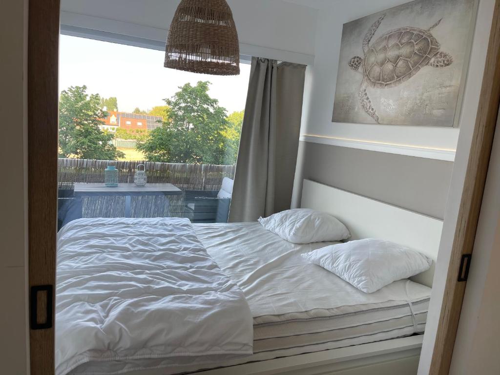- un lit avec deux oreillers dans une chambre dotée d'une fenêtre dans l'établissement Laguna Beach appart dans résidence avec piscine, à Knokke-Heist