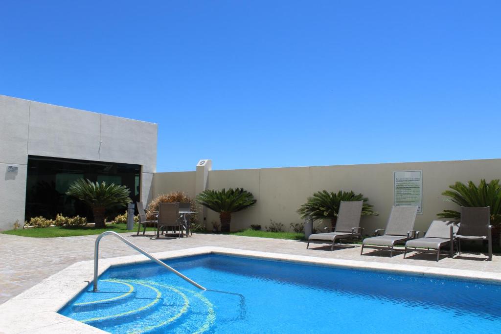 a swimming pool with chairs and a building at Hotel Aeropuerto Los Cabos in San José del Cabo