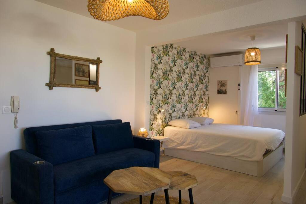 Un dormitorio con una cama y un sofá azul. en Studio Centre-Ville Saint Gilles Les Bains, en Saint-Gilles-les-Bains