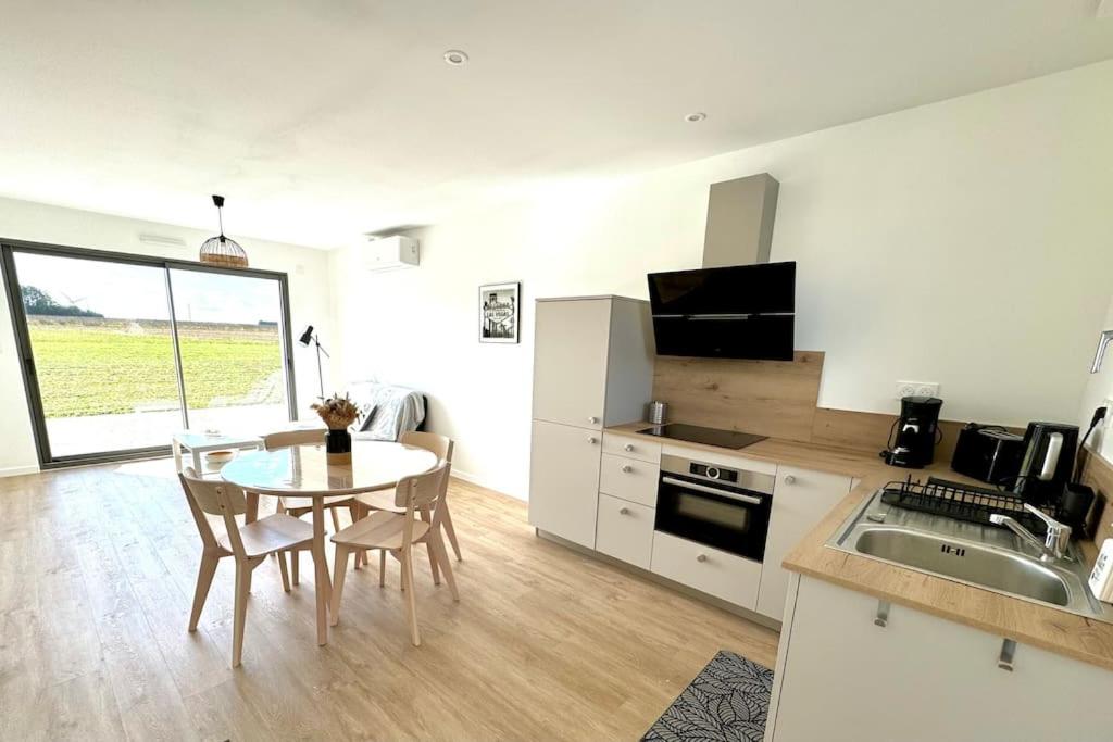 a kitchen and dining room with a table and chairs at Les Gites des jardins d'Oscar l'Appartement in La Faye