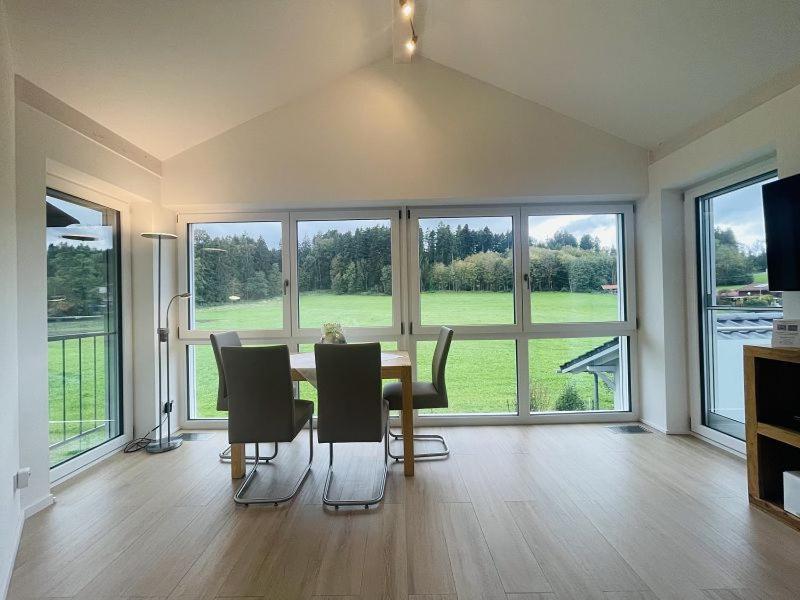 Un comedor con mesa y sillas y grandes ventanales. en Ferienwohnung Hoherting, en Prien am Chiemsee