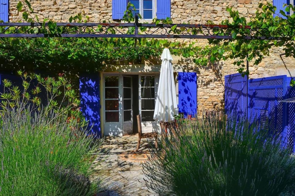 un parasol et des chaises devant un bâtiment dans l'établissement Charmant duplex bucolique, piscine, en Provence, à Le Beaucet