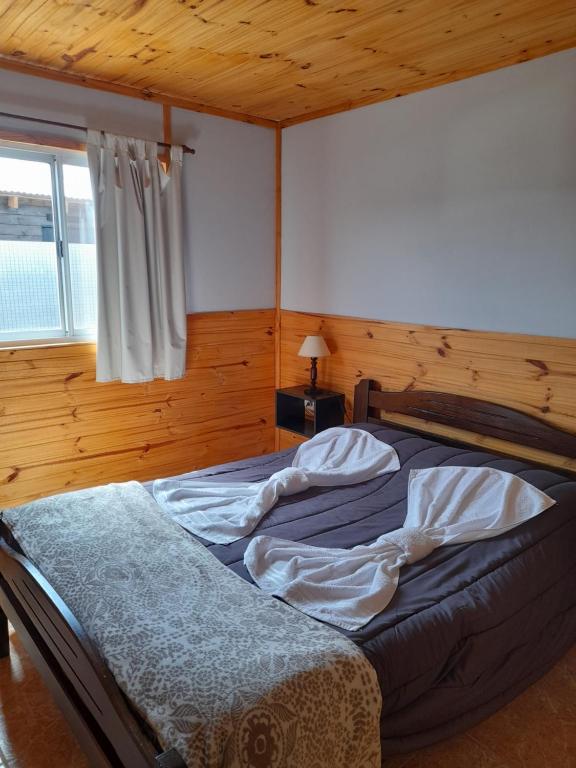 een bed in een slaapkamer met een houten plafond bij Los Nopo in Trevelín