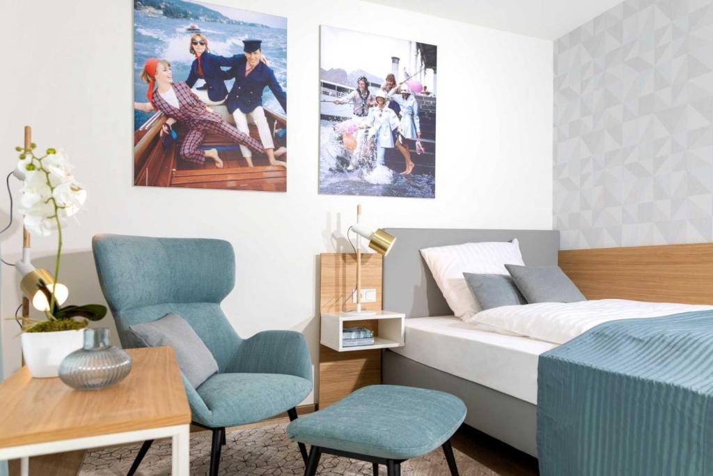 a bedroom with a bed and two blue chairs at NINO-Boardinghouse 23 in Nordhorn