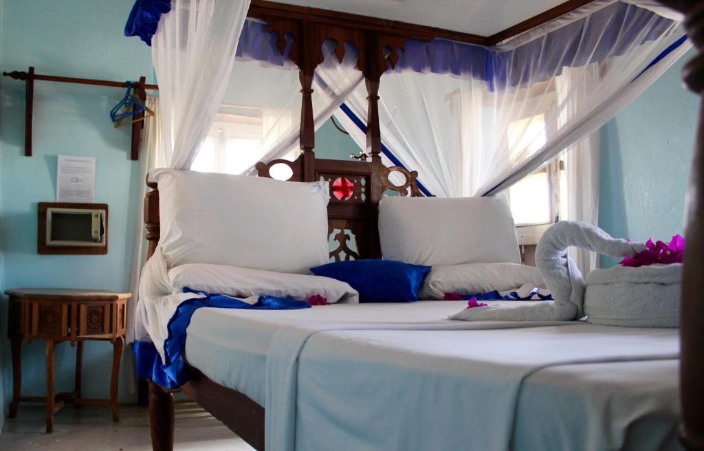 a bedroom with two beds with white and blue at Princess Salme Inn in Zanzibar City