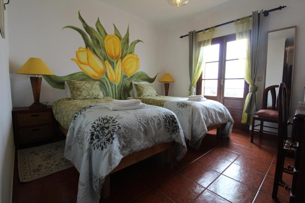 a bedroom with two beds with flowers on the wall at Quarto Tulipa in Vila Nova de Milfontes