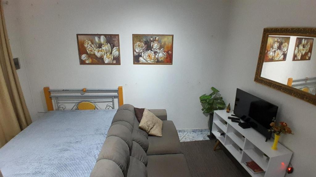 a bedroom with a bed and a couch and a mirror at Casa para 9P com escada sem garagem in Aparecida