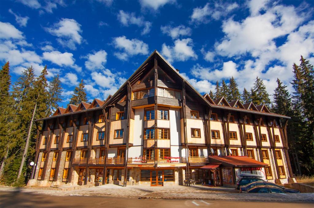 Un gran edificio con árboles al fondo. en Апартаменти Малина, en Pamporovo