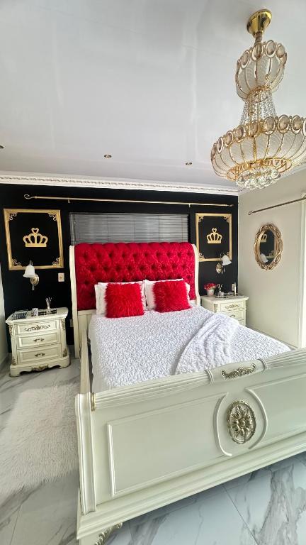 ein Schlafzimmer mit einem weißen Bett mit roten Kissen und einem Kronleuchter in der Unterkunft House of Royalty in Walmer