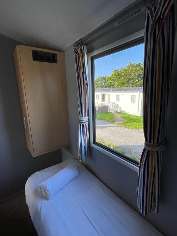 ein Bett in einem Zimmer mit Fenster in der Unterkunft Newquay Bay Holiday Resort Caravan 142 in Newquay Bay Resort