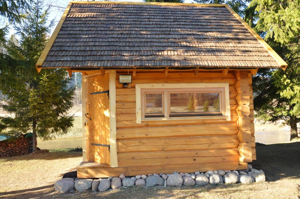 a small log cabin with a window and a roof at Ansomäe Puhkeala Järvemaja in Otepää