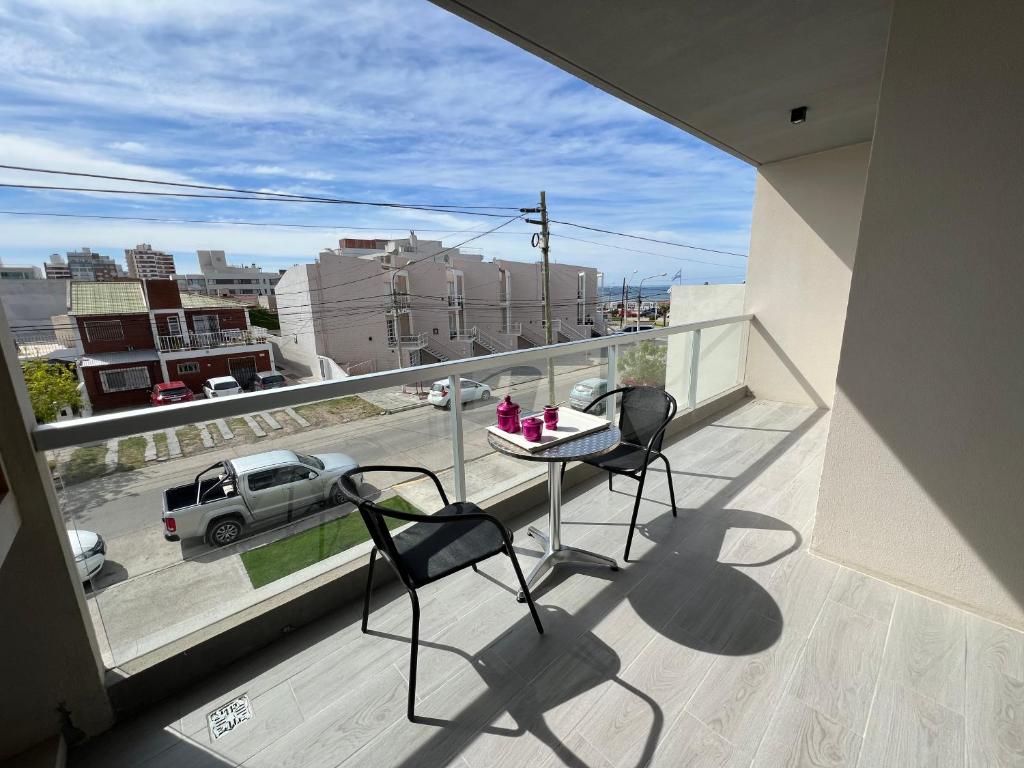 a balcony with two chairs and a table and a view of a street at Destino Mar in Puerto Madryn