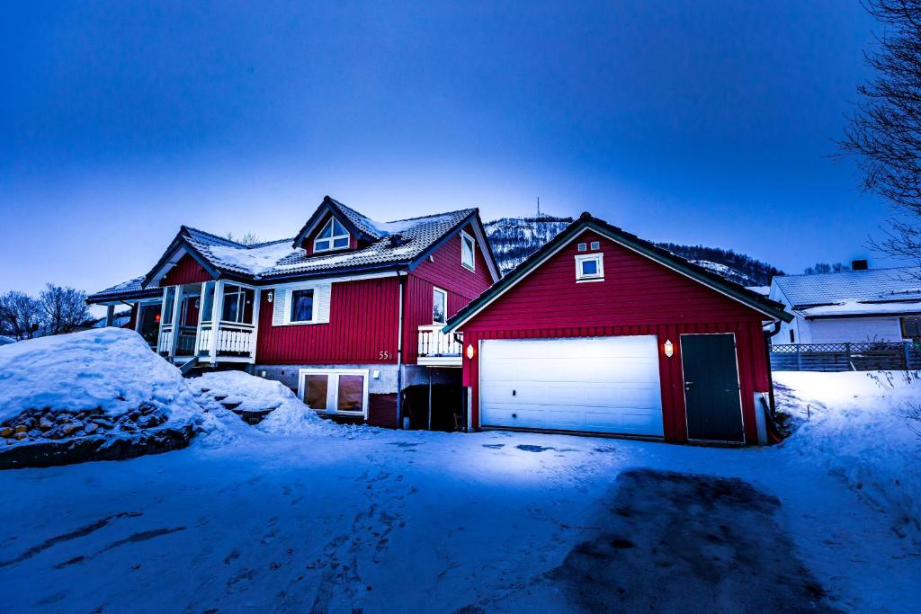 a red house with a garage in the snow at North apartments Tromsø 5 in Tromsø