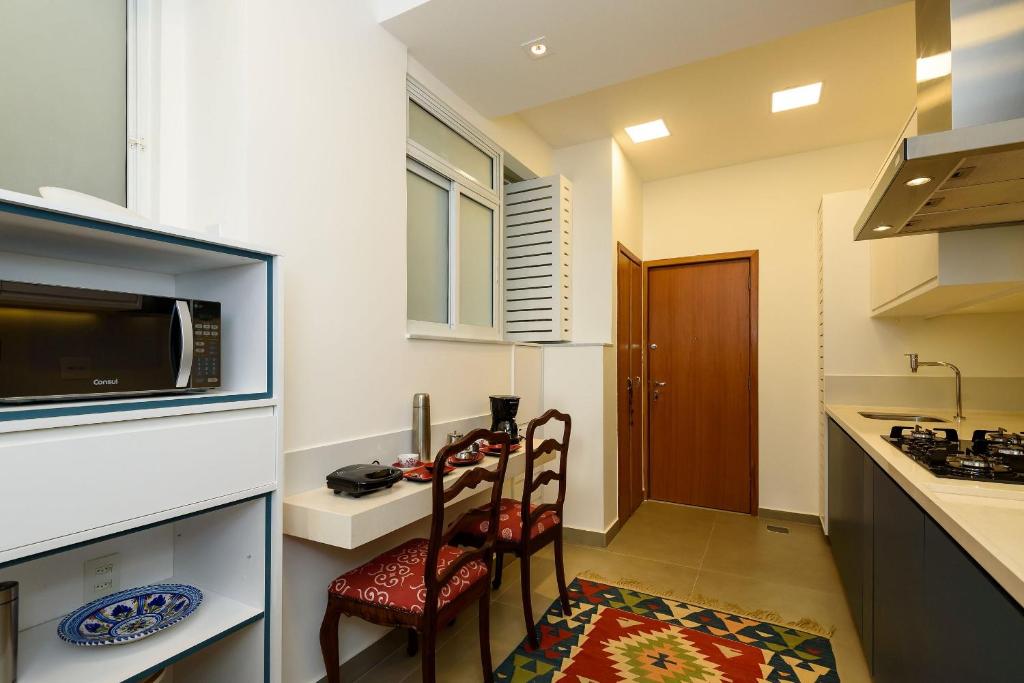 eine Küche mit 2 Stühlen und einem Tisch mit einer Mikrowelle in der Unterkunft Vista lateral mar, rua tranquila e arborizada in Rio de Janeiro