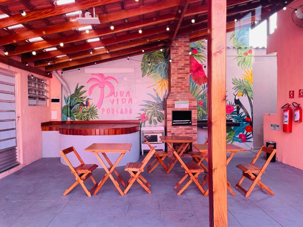 a restaurant with wooden tables and chairs and a wall at Pousada Pura Vida in Bertioga