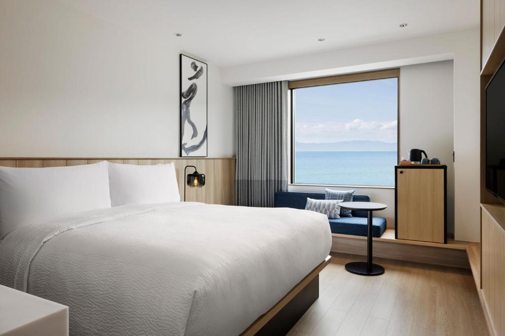 垂水市にあるFairfield by Marriott Kagoshima Sakurajimaのベッドがあり、海が見えるホテルの部屋