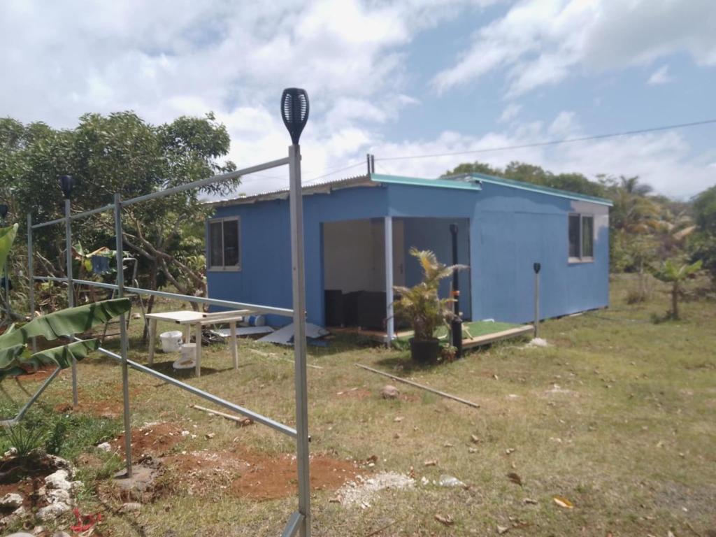 una casa azul en medio de un campo en Chez Qaeko, en Lifou